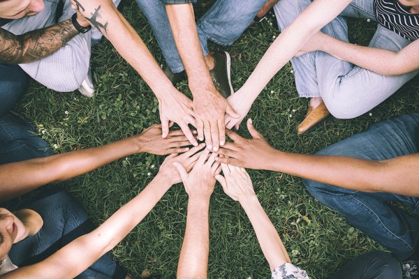 People stacking hands together in the park